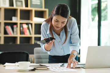 Smiling businesswoman talking on smartphone while waiting client in office