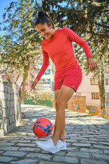vertical photo of a young woman playing soccer with a ball in bolivia latin america