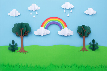 Paper art landscape background. Rainbow on blue sky with clouds and green tree made of paper cut. creative minimal concept.
