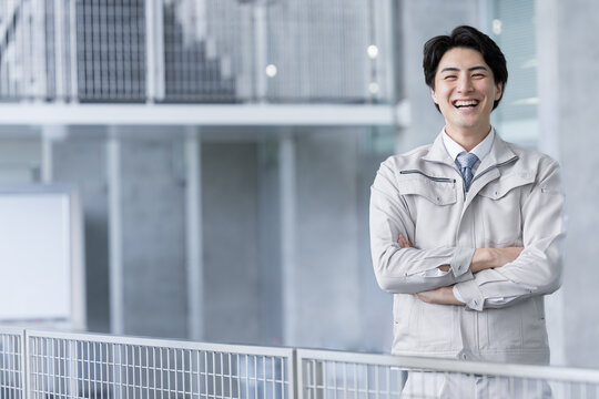 カメラ目線で腕を組む笑顔でハンサムな作業服を着た作業員　