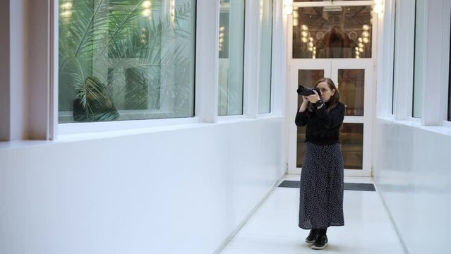 Concentrated Latin woman photographer in casual clothes taking photos with professional photo camera of National Art Museum of Catalonia on camera while visiting in Barcelona, Spain