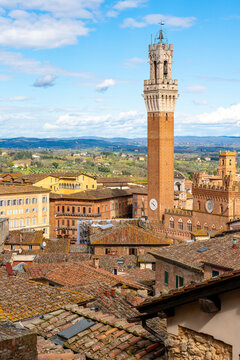 Daytime  cityscape view of the Tuscan town of Siena, Italy. View as seen from the top of the Duomo di Siena cathedral, with the Torre del Mangia tower prominent on the right side of the frame.

