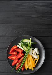 Fresh Vegetables Plate with tomatoes, cucumber, pepper, onion and green onion on dark wooden table, top view, flat lay. Vertical banner.