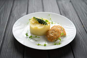 Chicken cutlet and mashed potatoes on a dark wooden background. The concept of a children's menu in a restaurant or cafe
