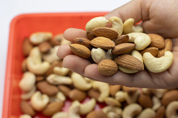 Close up shot of Almond and Cashew nuts in hand.