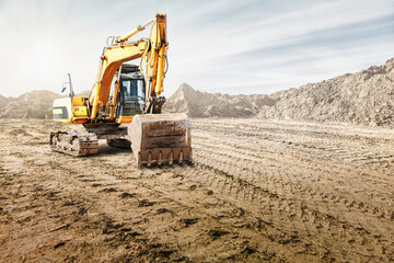 Crawler excavator works in a sand pit against the sky. Powerful earthmoving equipment. Excavation. Construction site. Rental of construction equipment. - obrazy, fototapety, plakaty