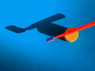 Fototapeta premium Bright orange toothbrush on a blue background. Dental care. Morning routine