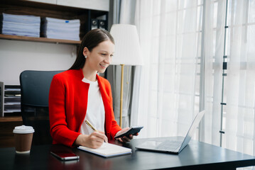  Beautiful woman using laptop and tablet while sitting at her working place. Concentrated at work..