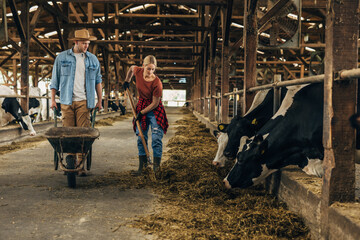 A female and male farmer clean the stable together.