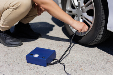 Obraz premium Man checking air pressure and filling air in the tires of car