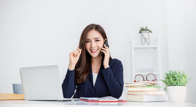 Portrait young asian business woman talk on smartphone write notebook laptop in home office. Beautiful asian girl at desk computer take home order. Startup business asia woman online sme telemarketing