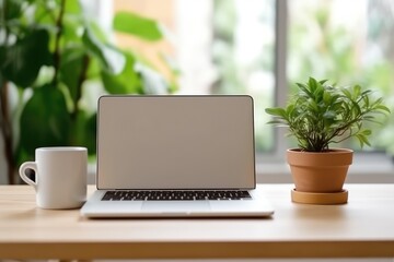A laptop with a white screen mockup on top of a desk, a cup of coffee and minimalist room decorations