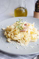 homemade fettuccine pasta with white cream sauce. Carbonara fettuccine, hard cheese, dried pork, black pepper. Italian food. 