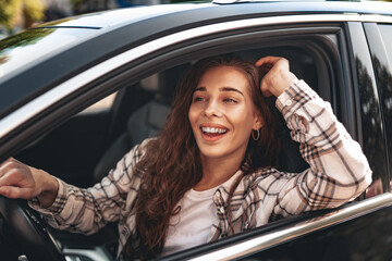 Young smiling woman driving a car in the city