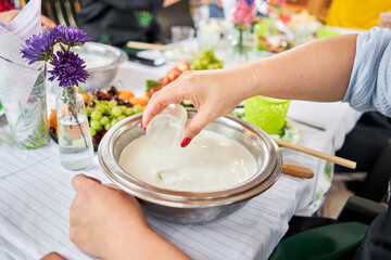 Making cheese from goat milk at home. Female and stir cheese sourdough with a spoon in a saucepan. Technology of cooking cheese. Cheese-making processes. Cooking concept