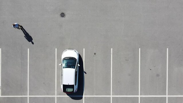 aerial view as a man goes to the car and leaves parking place
