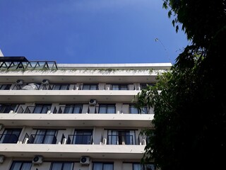 minimalist window of a multi room building with air conditioning taken from below and blue sky background