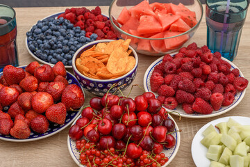 świeże kolorowe owoce na stole, pełne talerze, doskonała zdrowa i dietetyczna przekąska na imprezę  - obrazy, fototapety, plakaty
