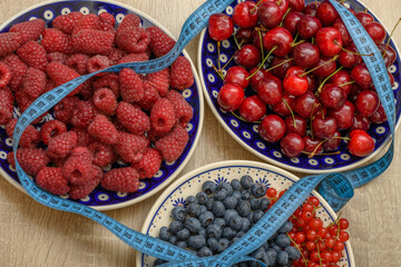 Talerze wypełnione świeżymi owocami - maliny, jagody i czereśnie