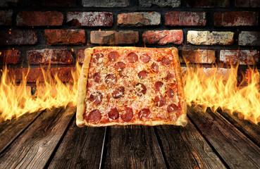 Square pepperoni pizza on wood table with fire and vintage brick in the background