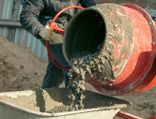 Worker pouring concrete with cement mixer at construction site, closeup - obrazy, fototapety, plakaty