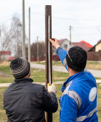 Obraz premium Workers install a metal profile fence