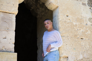 Obraz na płótnie Canvas Non binary latin and young person, is in a castle making different body expressions in the hole of the door. Concept of diversity, homosexuality and gay pride.