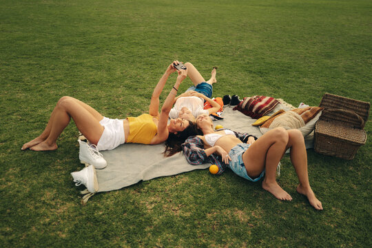 Three friends taking selfies on a picnic at the park