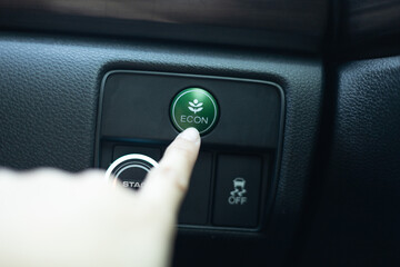 Close-up woman's hand is pressing the fuel economy  or ECO button for the vehicle's fuel economy....