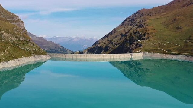 Moiry, Switzerland: Aerial drone footage of the Moiry dam above the Grimentz village in the Anniviers valley in Canton Valais in the Swiss alps in summer. Shot with a forward tilt down motion. 