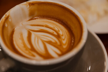 Close up a cup of hot latte art coffee on wooden table.A cappuccino is an espresso-based coffee drink with steamed milk foam.Best of menu in the coffee shop or restaurant.
