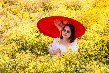 Asian woman wears white dress, happiness in yellow flower garden.