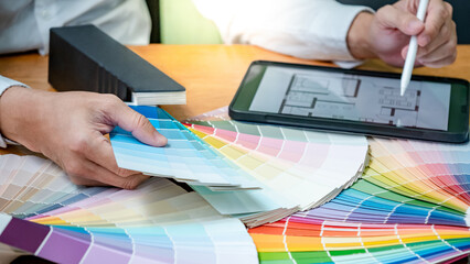 Designer hand choosing and pointing at color swatch or rainbow colour palette guide while working...