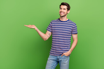 Photo of young promoter advertiser man holding arm proposition object look interested commerce deal isolated on green color background
