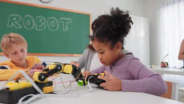 Smart primary students grouping to learning robot free electives with female teacher in classroom. Caucasian teacher female teach childrens assemble robot in science subject at elementary school.