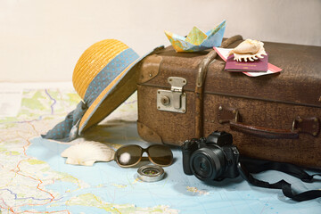 Summer vacation with a vintage suitcase, straw hat, camera, sunglasses, passport and a small paper...