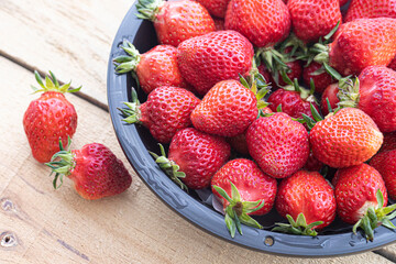 Fresh strawberry packed in black plastic bowl.