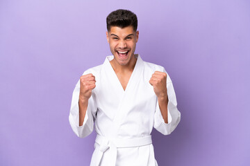 Young caucasian man doing karate isolated on purple background celebrating a victory in winner position