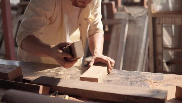 A carpenter polishing a prank of wood with sandpaper by hand. Carpentry, Craftsmanship, woodworking.