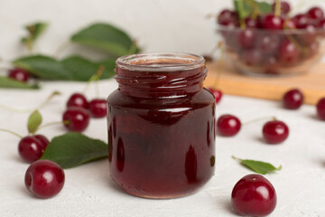 Jar with tasty homemade cherry jam on wooden table