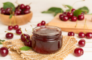 Jar with tasty homemade cherry jam on wooden table