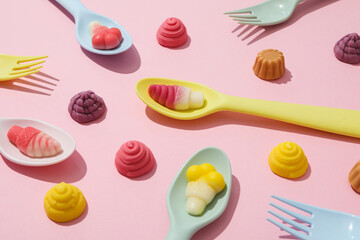 Jelly candies and plastic cutlery on pink background