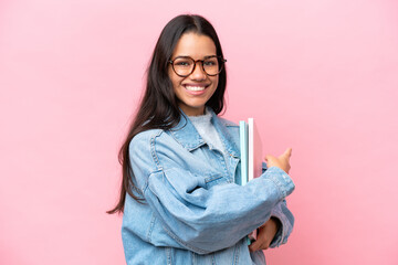 Young student Colombian woman isolated on pink background pointing back