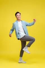 Young handsome man standing over isolated yellow background very happy and excited doing winner gesture with arms raised