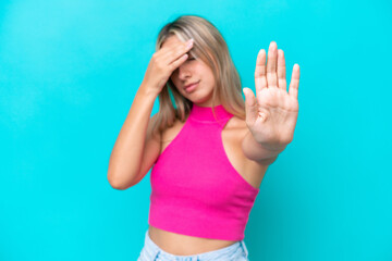 Young caucasian woman isolated on blue background making stop gesture and covering face