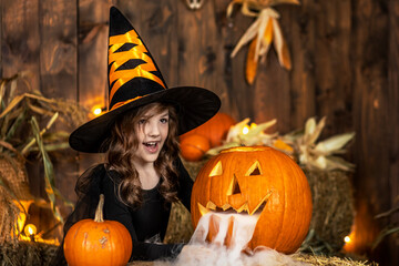 Cute little witch girl posing in halloween scenery. Halloween Party.
