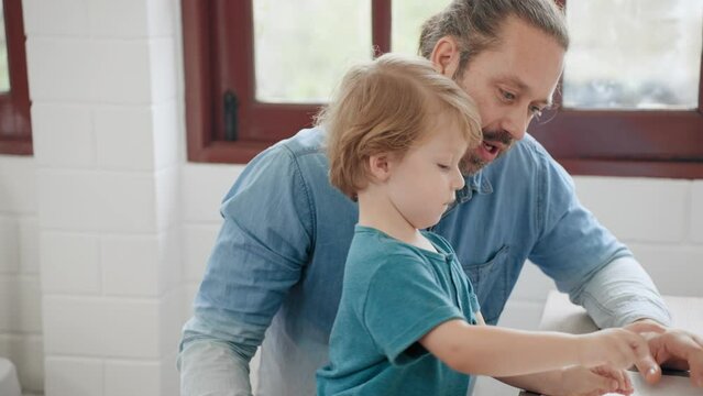 Caucasian father teaching and drawing picture with little boy together at home. Good dad using spare time with son on holiday at home. Family relationship concept.