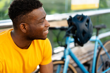 Fototapeta na wymiar Smiling african american man looking away while relaxing with bicycle at the street