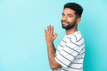 Young Brazilian man isolated on blue background scheming something