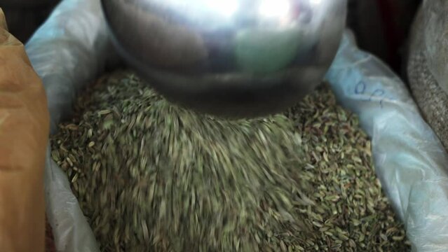 cumins seeds in local market bag segregating with metal spoon 